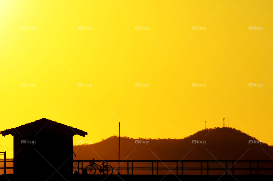 Silhouette of house and mountain at sunset