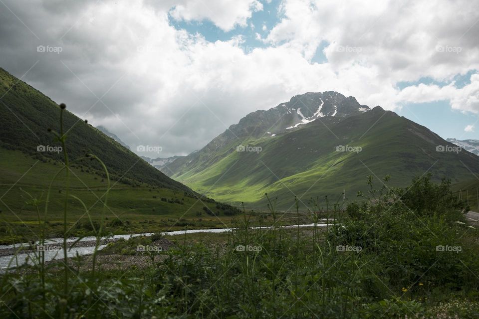 Beautiful landscape with green mountains and  cloudy sky.