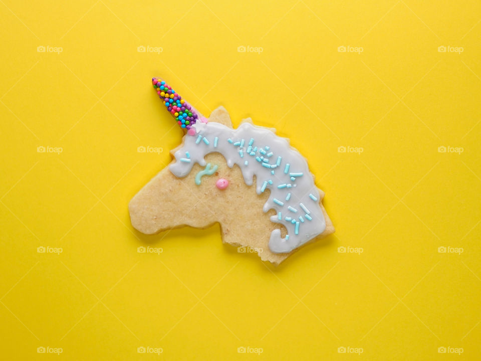 Vegan unicorn shaped cookie with colourful sprinkles.