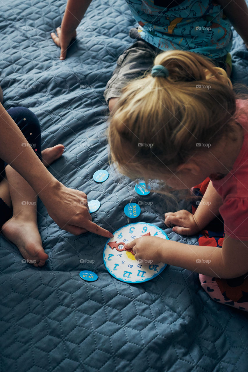 Kids learning how to tell time from clock and set the hands in the correct position. Teaching preschoolers tell time. Candid people, real moments, authentic situations