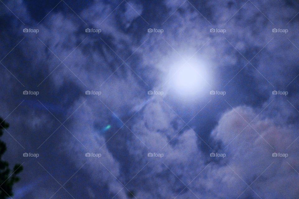 The moonlight looks bright among the clouds that almost cover it after the rain fell in the afternoon