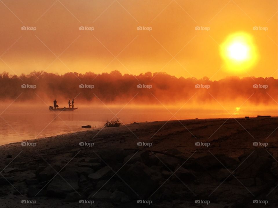 Orange Sunrise on a Misty Lake with Men Fishing in a Boat