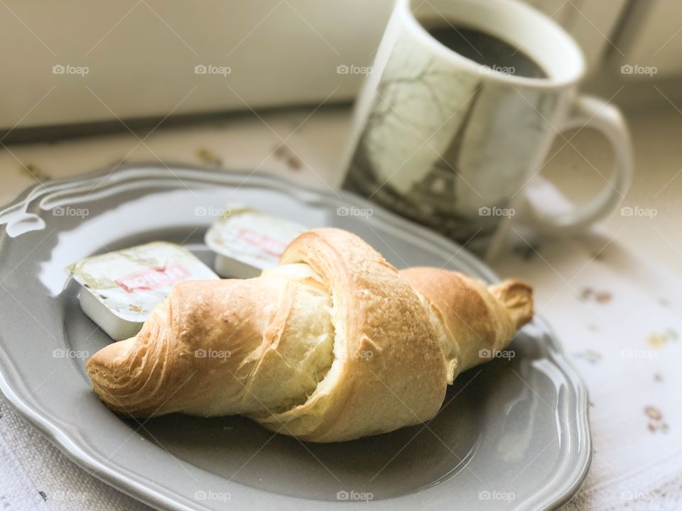A cup of coffee and croissant.