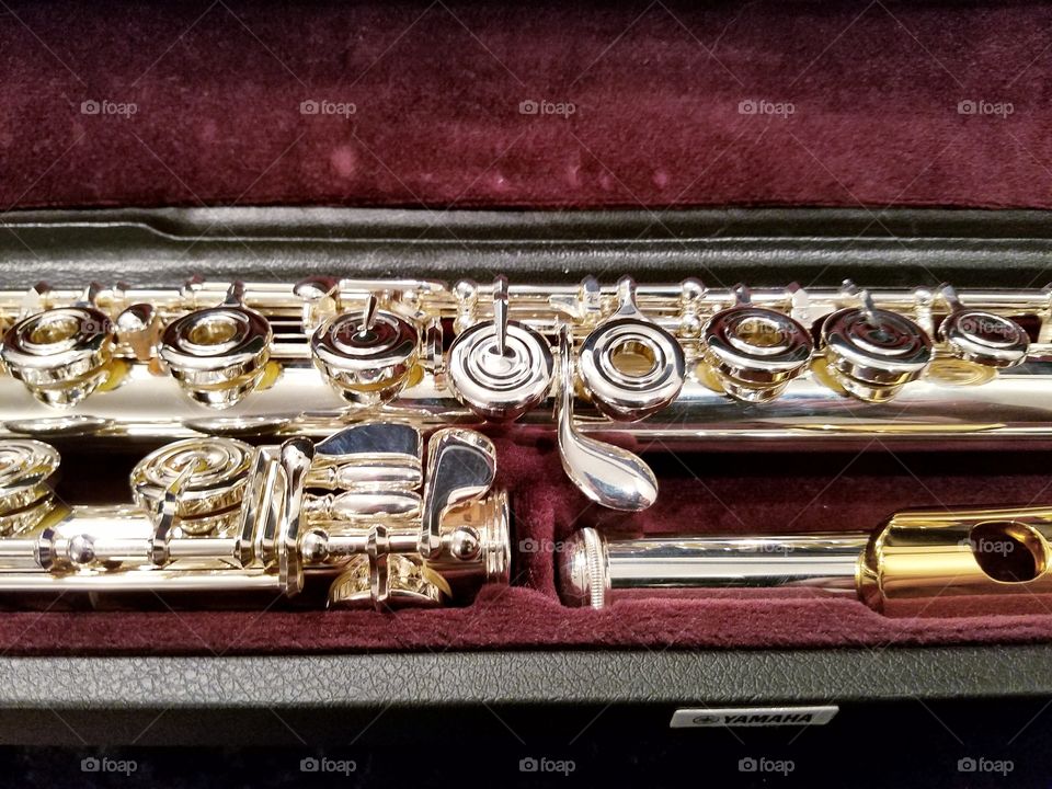 A gleaming, highly polished silver flute with a gold lip plate.