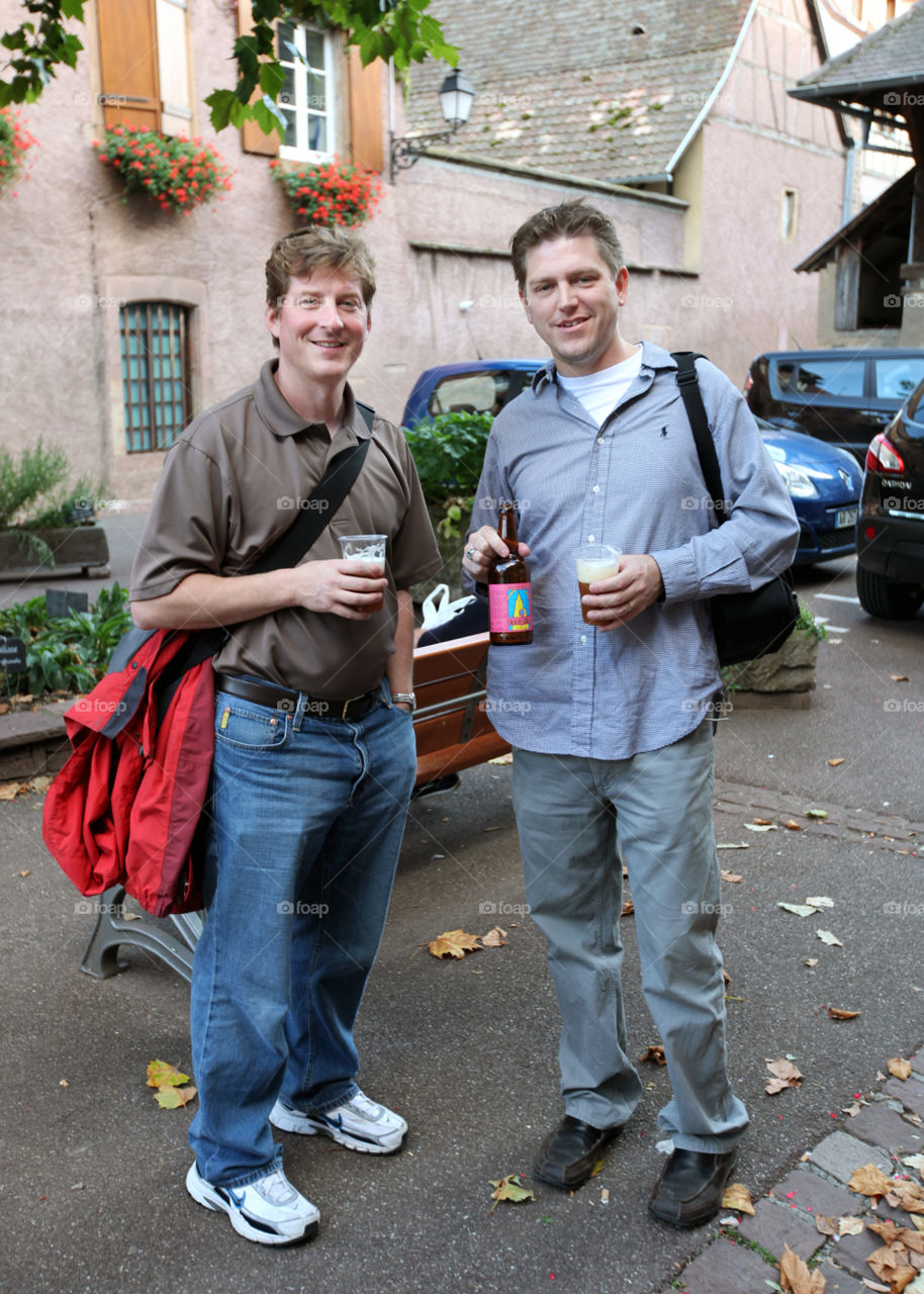 two men walking in france drinking a beer