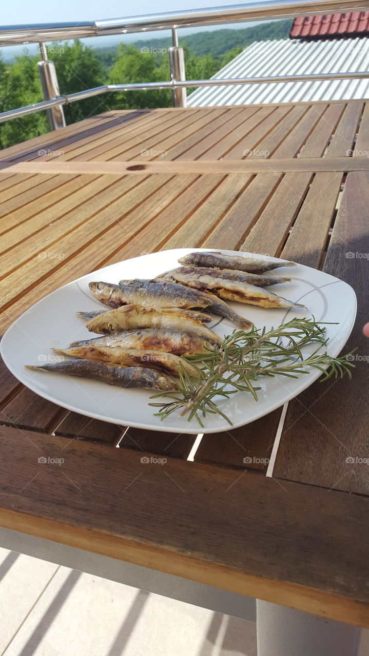 fresh fried sardines on a plate with rosemary