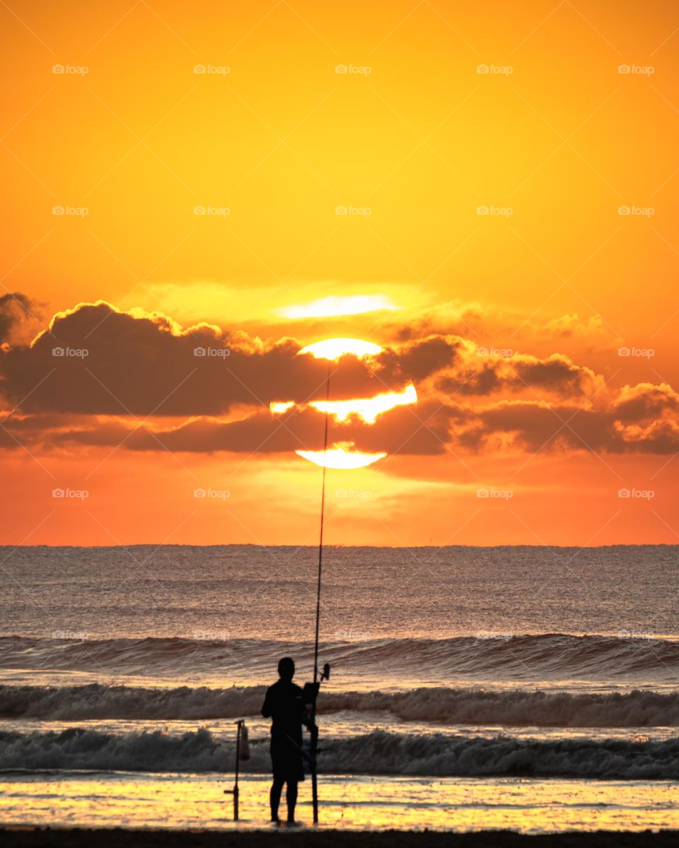 Pescador na praia ao amanhecer