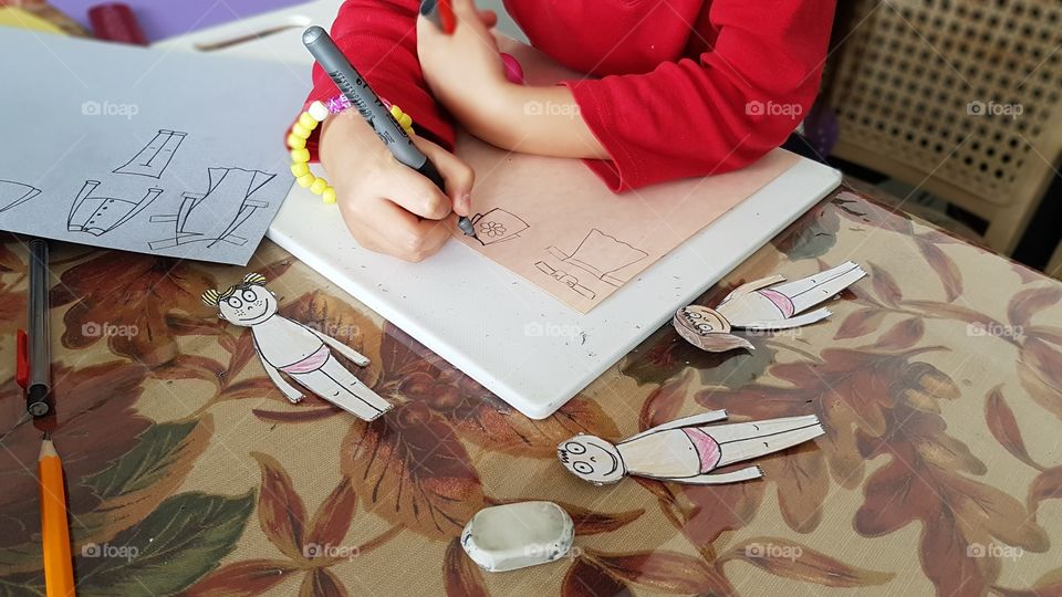 Girl is drawing clothing to dress paper people