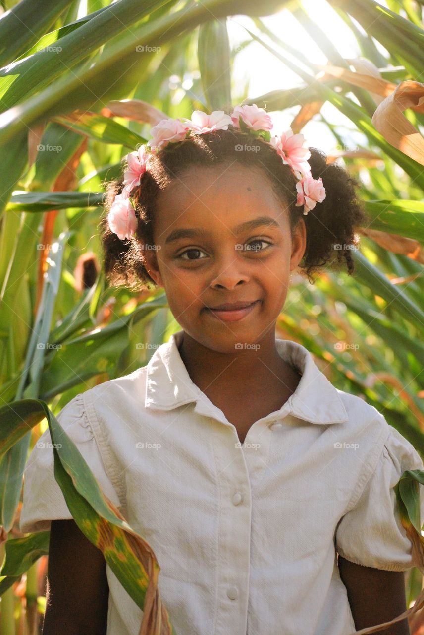 Little boho girl of mixed race wearing flowers in het curly hair