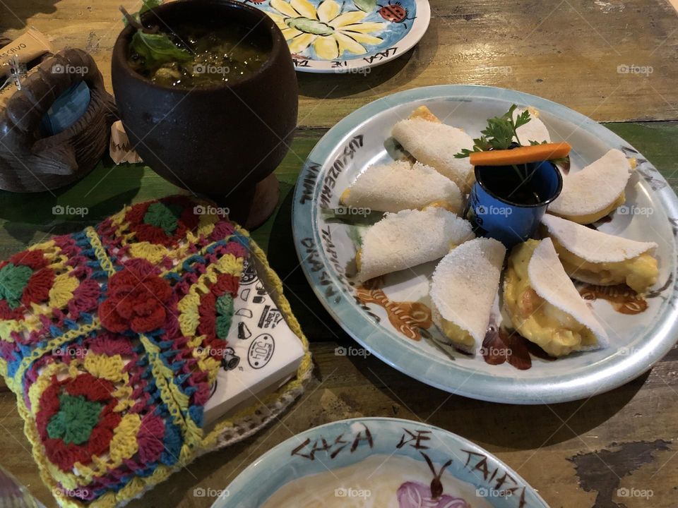 Shrimp tapiocas and a caipirinha in a colorful table