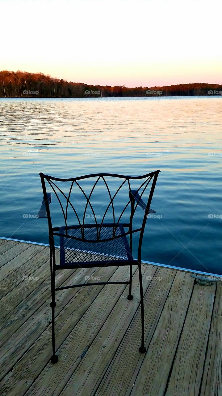 chair to relax on.  floating dock on a lake overlooking an island during dawn.