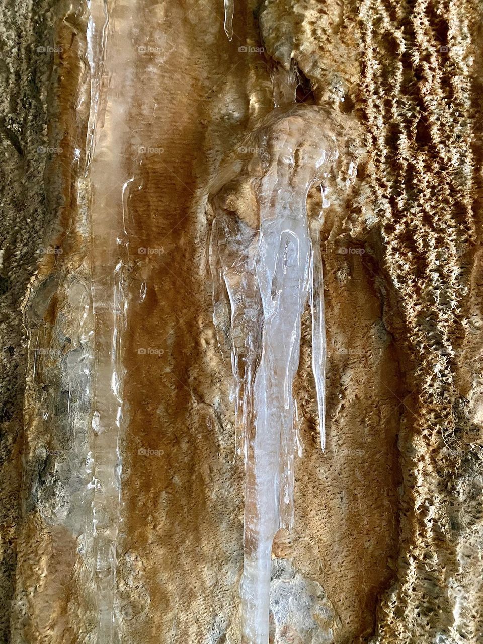 Ice and mineral deposits on the side of a tunnel formed from water coming out of a pipe