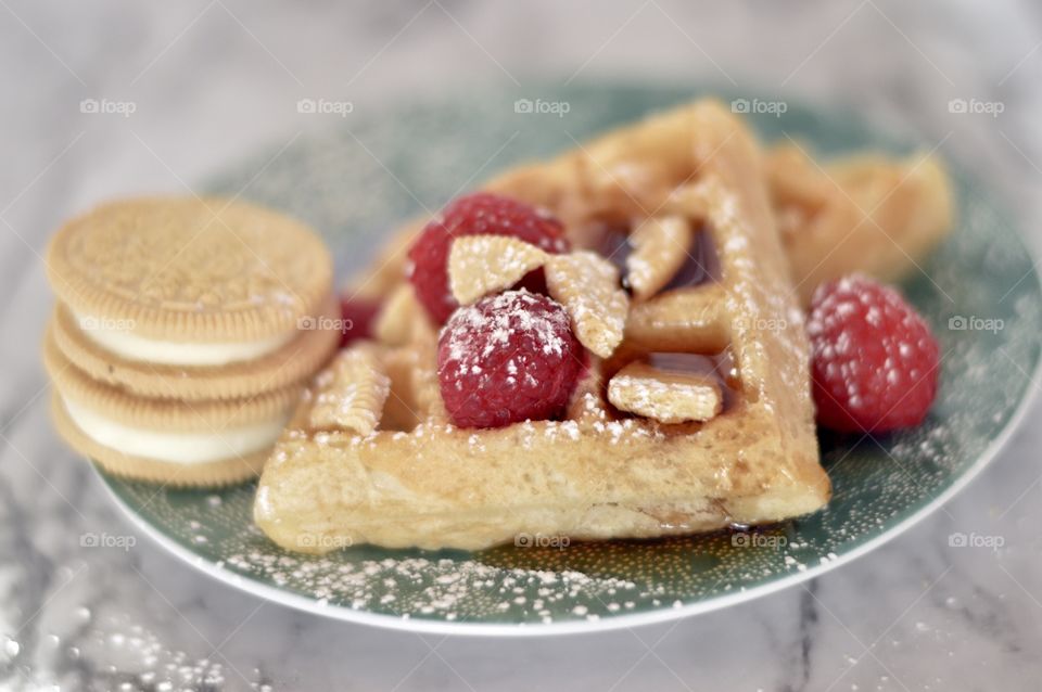 Golden double stuff Oreo cookies and a waffle with raspberries and powdered sugar