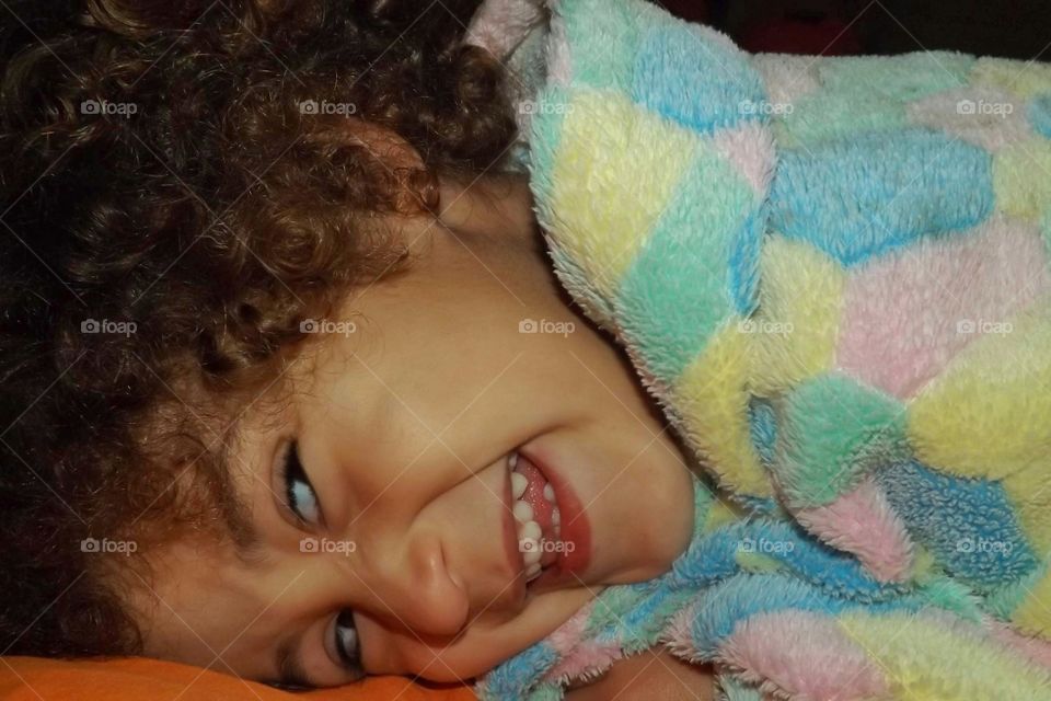 Girl lying down smiling with her favorite blanket