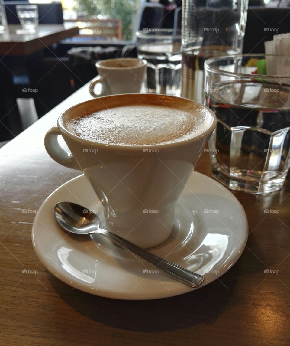 cappuccino and espresso with water glasses and water bottle on a tabe