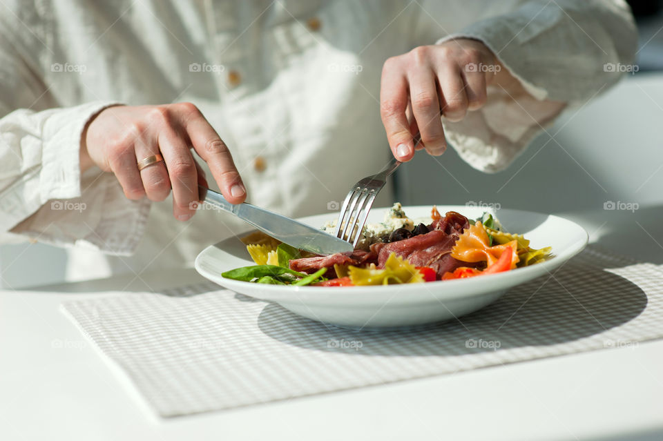 close-up of a young man eating a salad in a light kitchen
