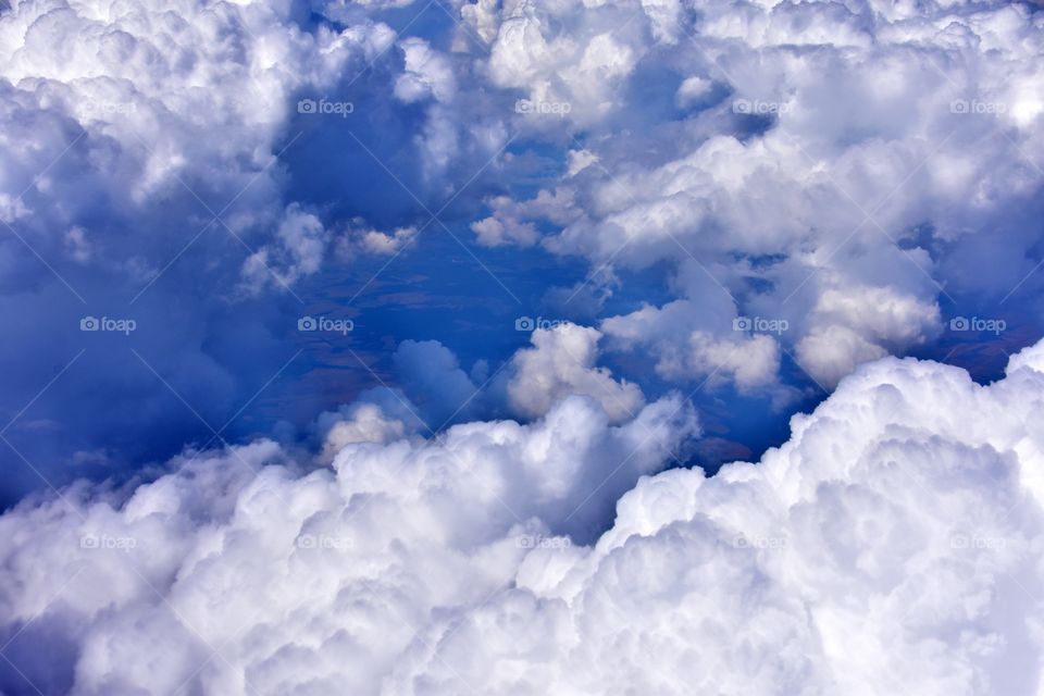 white fluffy clouds on the blue sky from plane window