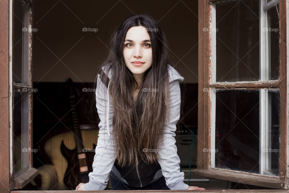 Beautiful young woman on the old window