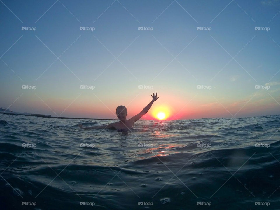 Girl floating in the sea, sunrise