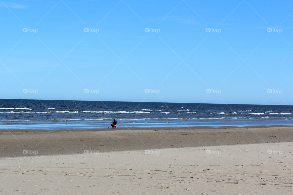 Baltic seascape with photographing on a tablet girl with a cup of coffee. Spring