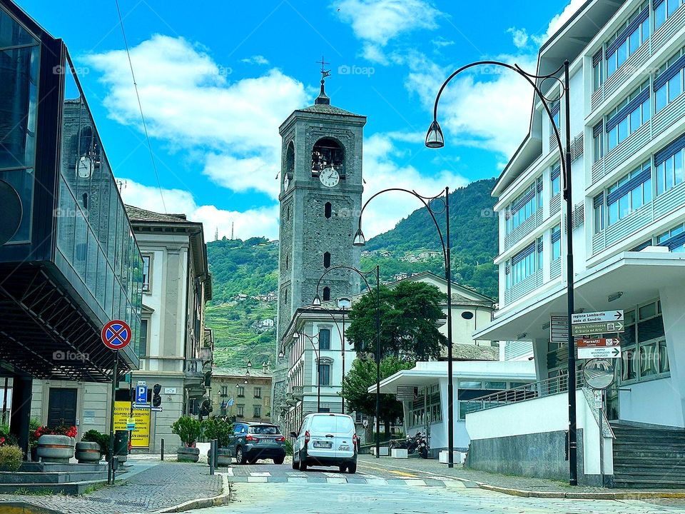 Trips.  Travelling by car.  Houses and a chapel are visible from the windshield of the car.  Mountains in the background