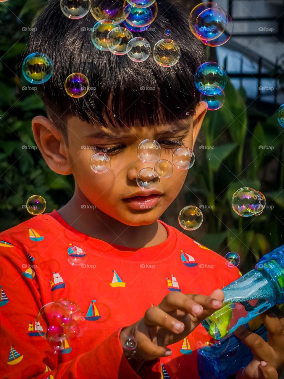 Little kid playing with bubble gun and popping up the bubbles