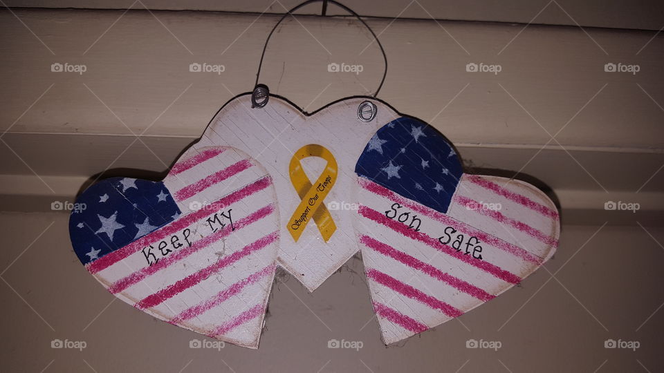Wooden hearts of the American flag hanging up over the door. In support of our military troops and asking to keep our sons safe. Heart in the middle is white with a yellow ribbon.