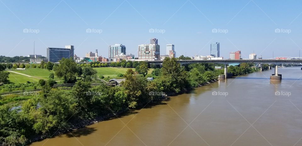 A scene of a city and a river in Arkansas, shot from a bridge.
