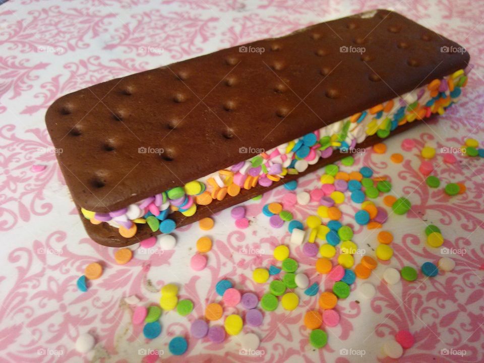 ice cream sandwich. ice cream sandwich with rainbow sprinkles on a pink and white damask background