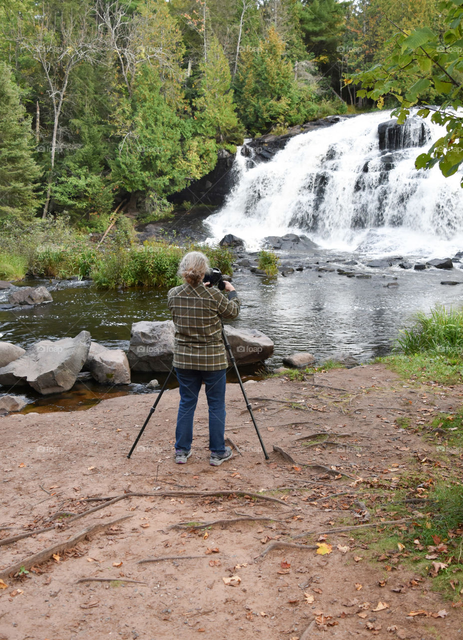 Woman photographing a waterfall