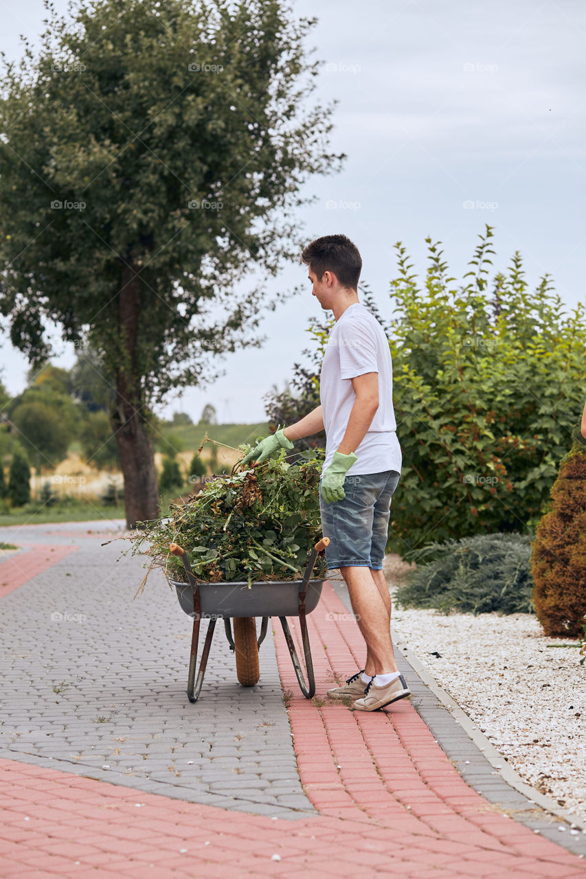 Teenage boy working at a home garden. Candid people, real moments, authentic situations