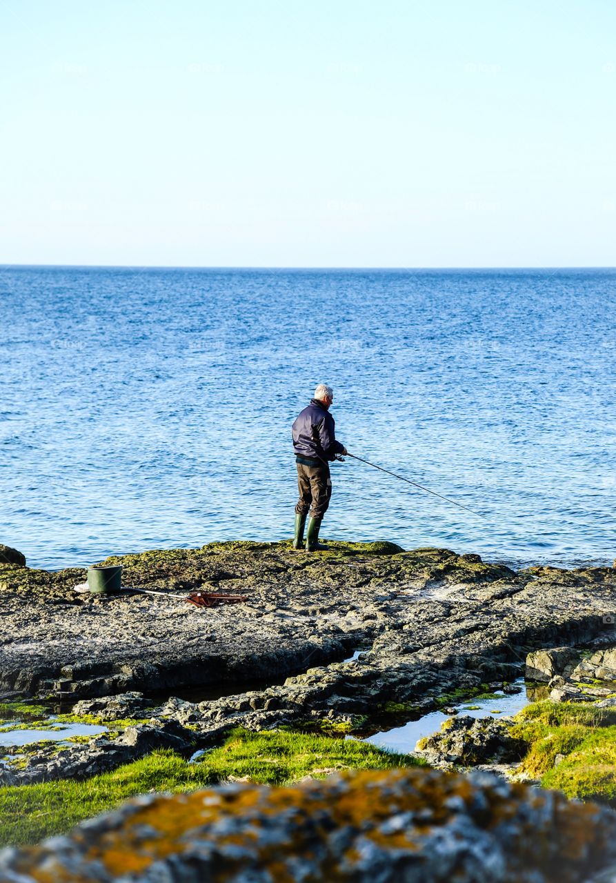 Fishing man. Fishing man standing alone on a cliff