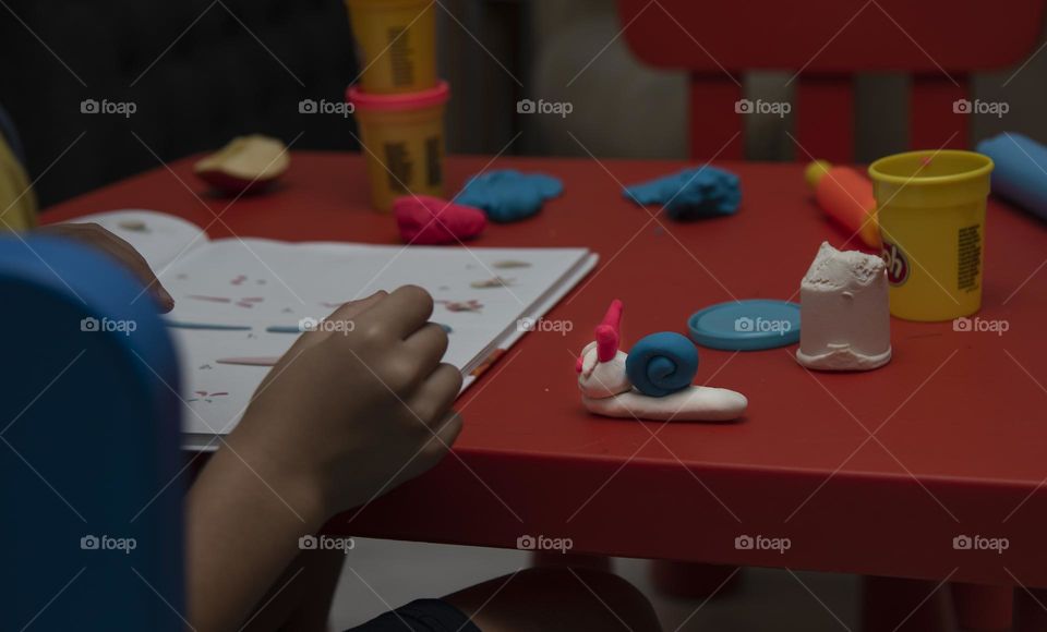 a boy sculpts a snail from plasticine
