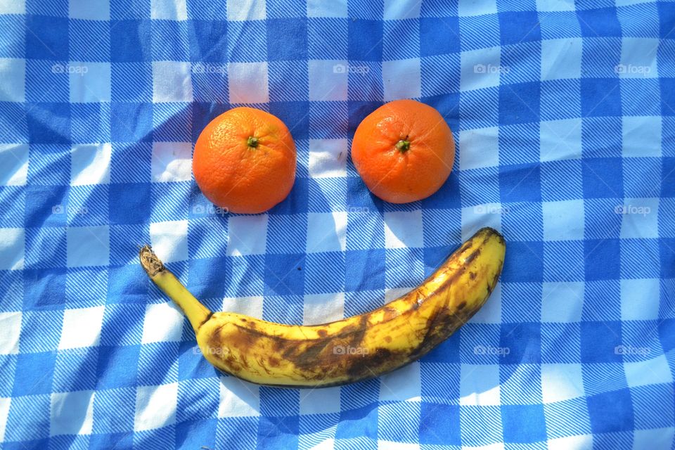 Two oranges and one banana simulating a smiling face