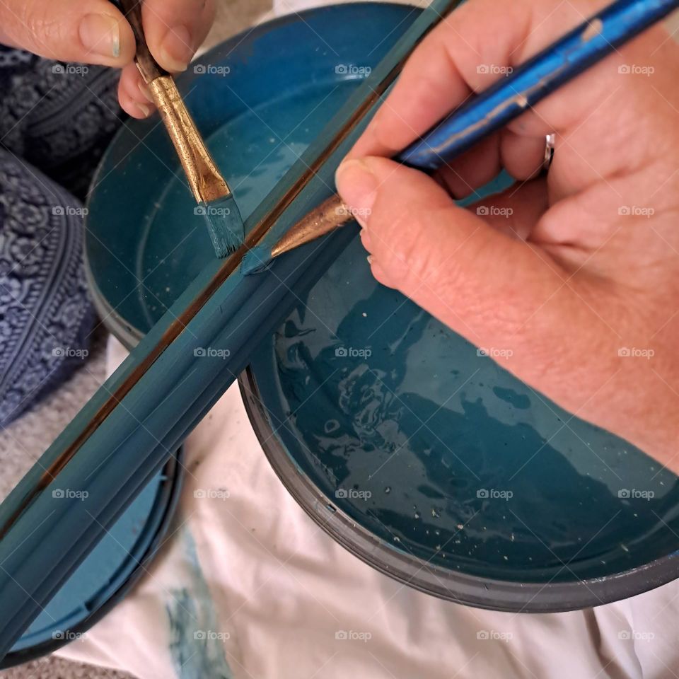 hand relection in mirror painting the frame wirh blue paint. painting. diy. paintbrush