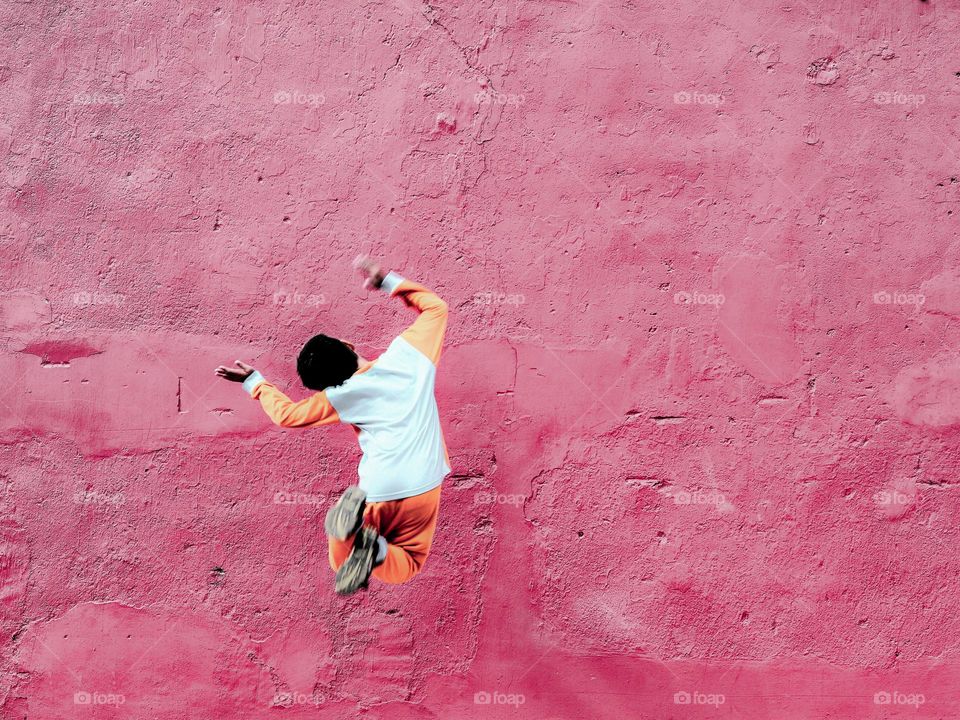 A boy doing a jumping joy act infront of a wall in Melaka, Malaysia