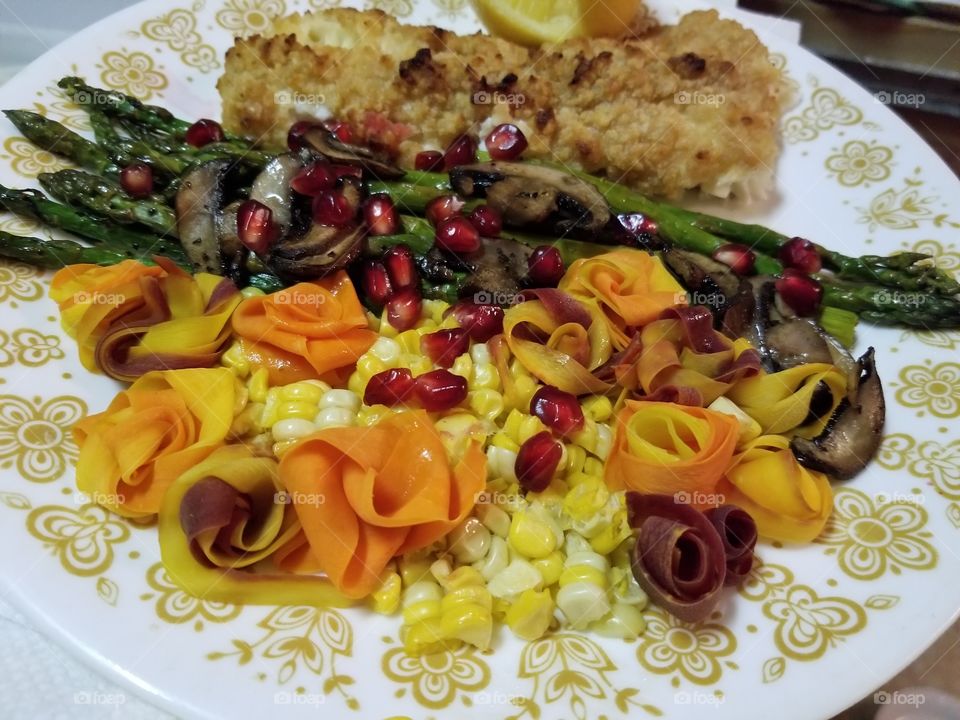 Baked haddock with seasonal vegetables. The rainbow carrot slices were folded into roses. Fresh pomegranate arils add color and texture i addition to a sweet and slightly tart surprise.