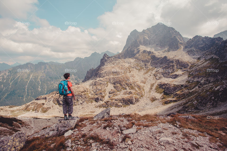Teenager boy with backpack and looking at mountain
