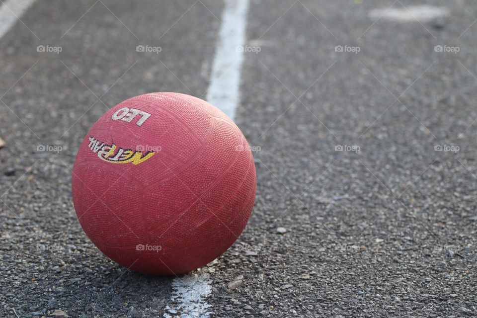 Close up view of a red ball on a white line in a basketball court 