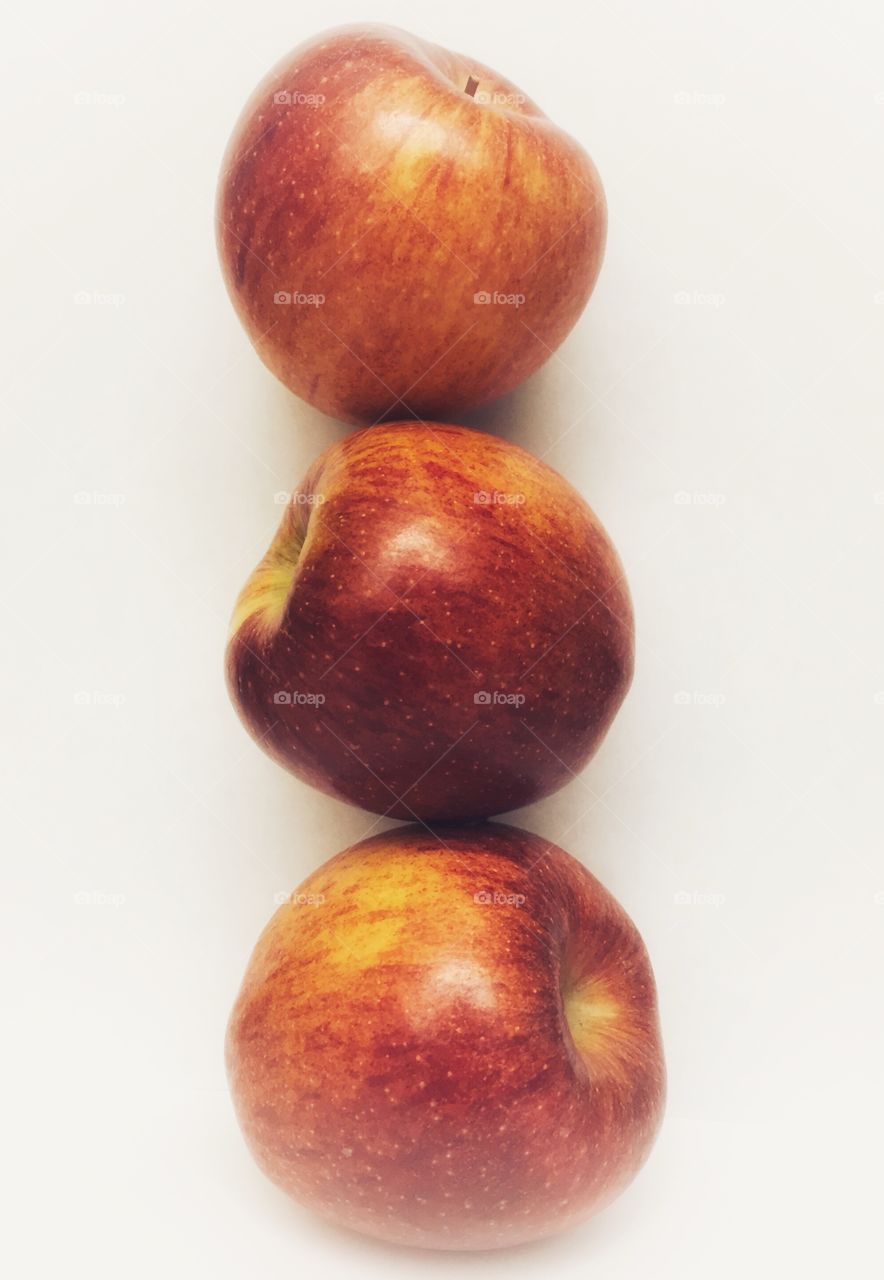 A balanced stack of three red apples