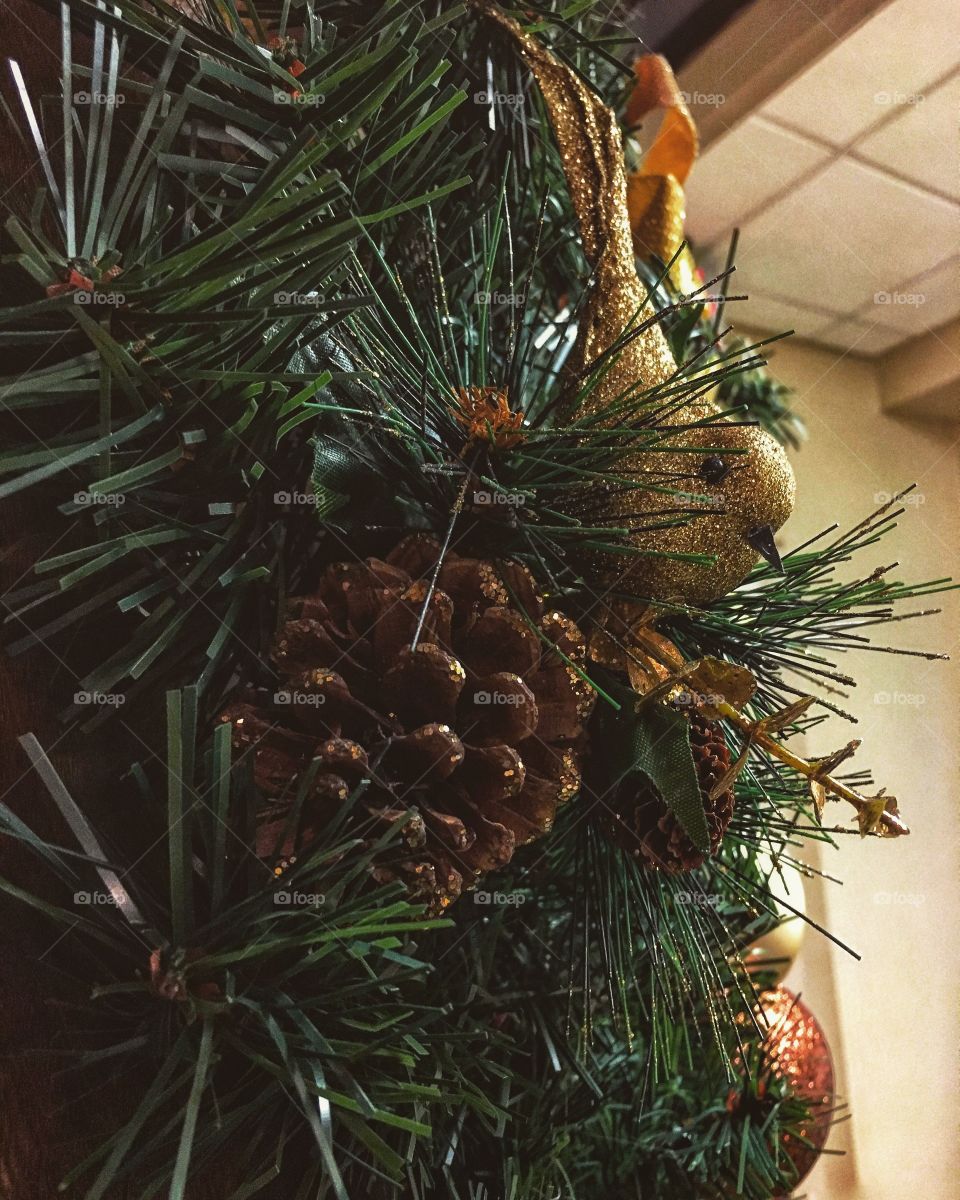 Gold birdie and pine cone sitting on a wreath