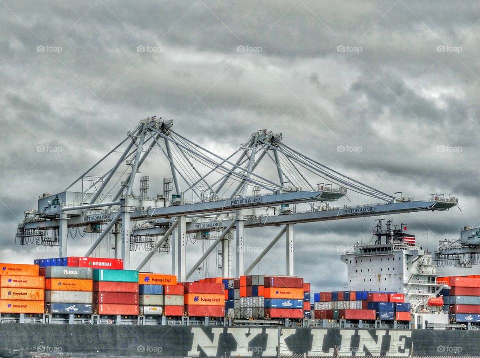 Cargo Ship Unloading Containers On Giant Cranes. Cargo Ship Unloading At A Seaport
