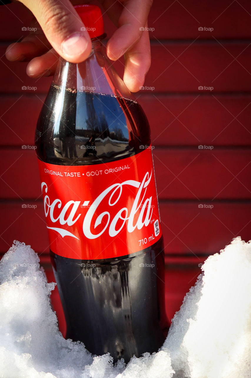 Hand grabbing a bottle of Coca-Cola