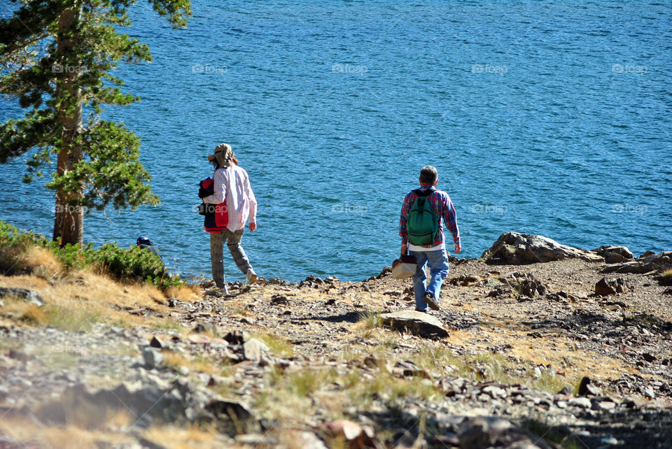 A man and a lady walking at the lake shore, getting ready for fishing