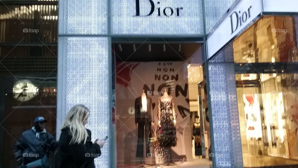 Woman with cell phone in front of Dior shop