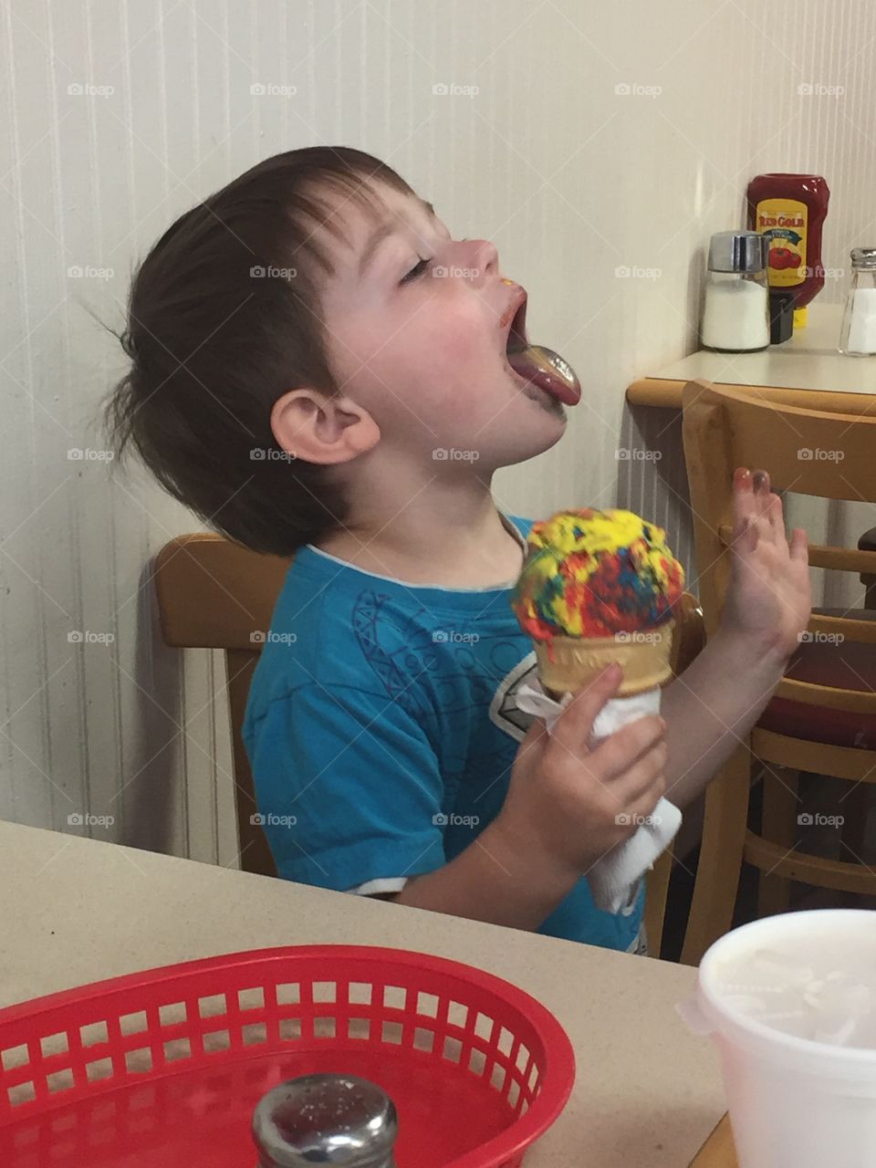 Little boy sitting on chair with ice cream cone