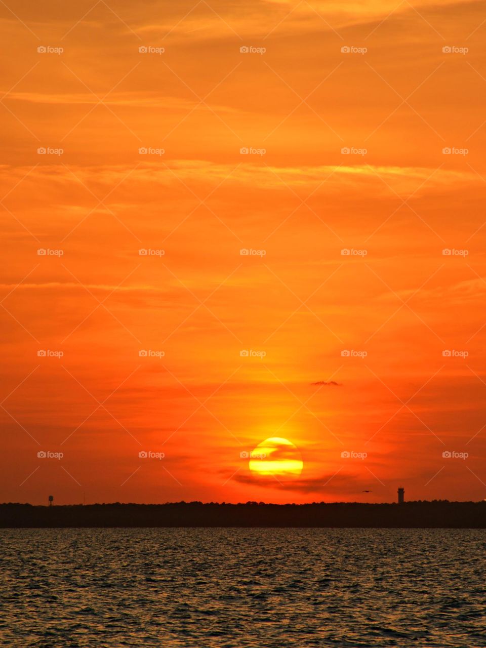 The big orange and yellow ball slowly going down and down and it sets into the horizon making the sky absolutely stunning