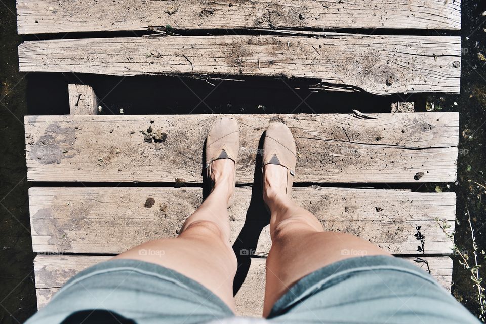 View of woman's feet on broken wooden pier