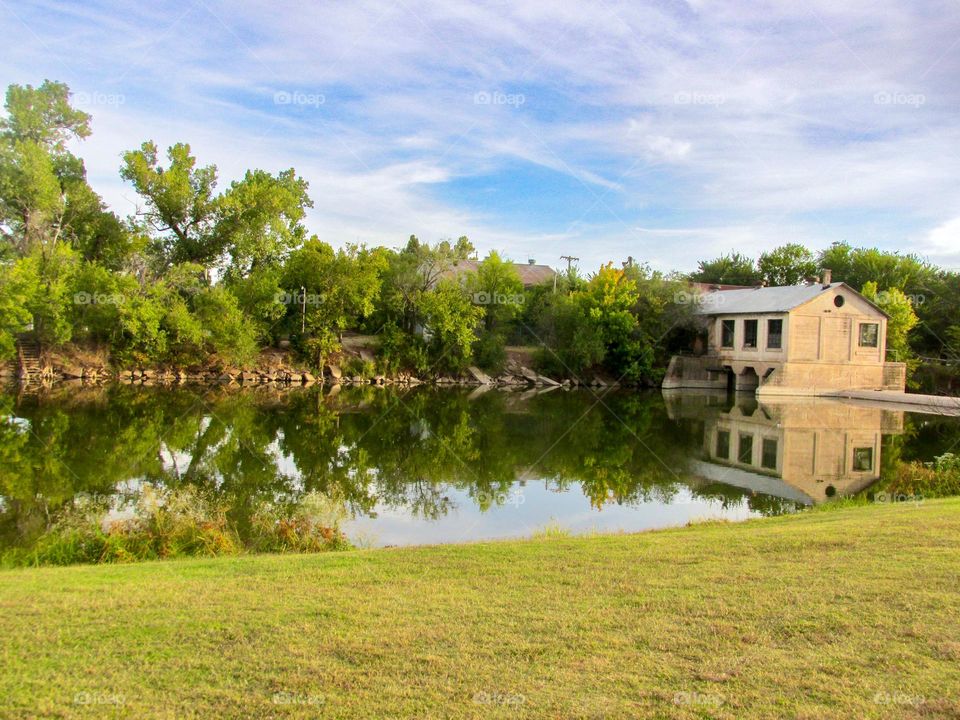 An old factory on the water with beautiful green trees 