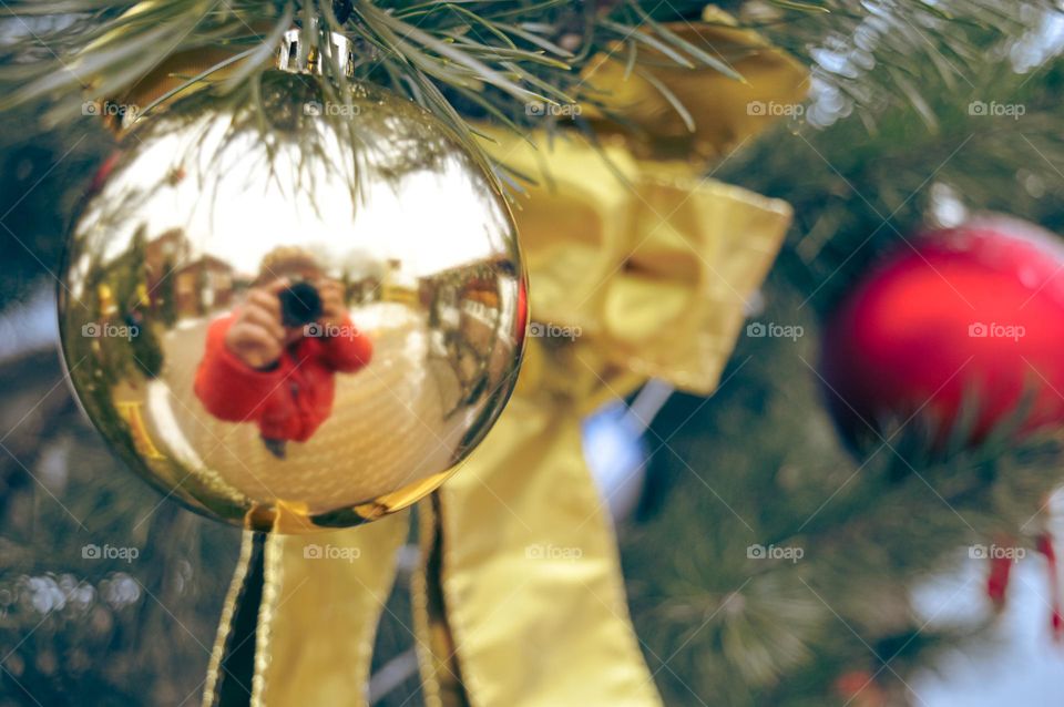 The golden toy on the New Year tree reflects the photographer